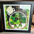 Handmade plant terrarium layered paper shadow box with potted plants and vines in a black frame