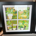 Handmade four-pane plant window layered paper shadow box with hanging planters and potted plants in a black frame